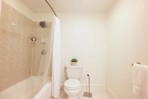 a white toilet sitting next to a bath tub and a shower