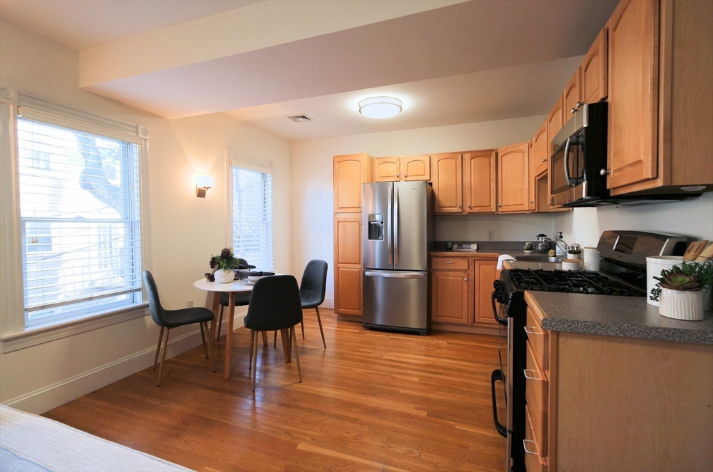 296 West 3rd Street, Unit U1 Boston, MA 02127 - Photo 4 of 22 a kitchen with stainless steel appliances granite countertop a refrigerator a stove a sink a dining table and chairs with wooden floor
