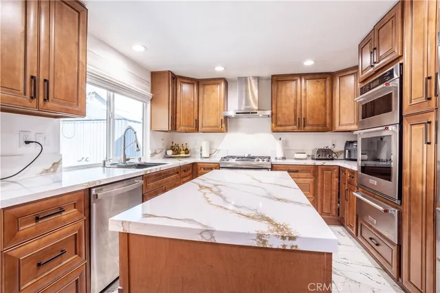 a kitchen with stainless steel appliances granite countertop wooden cabinets a sink and dishwasher a stove with wooden floor