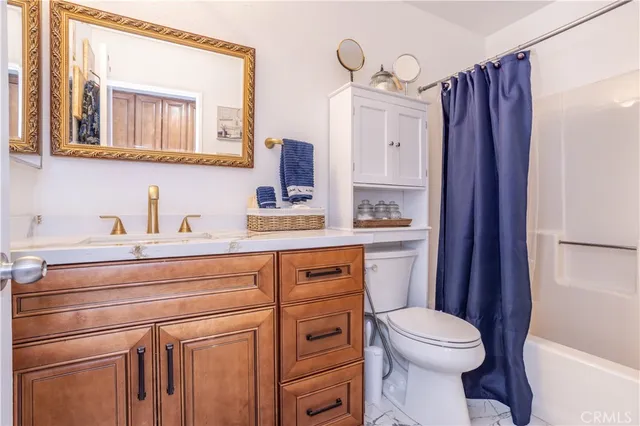 a bathroom with a sink a toilet a mirror a vanity and shower