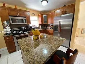 a kitchen with stainless steel appliances granite countertop a sink a stove a microwave a refrigerator and a microwave