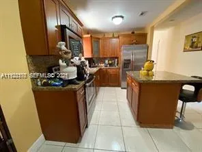 a kitchen with stainless steel appliances granite countertop a refrigerator a sink and wooden cabinets