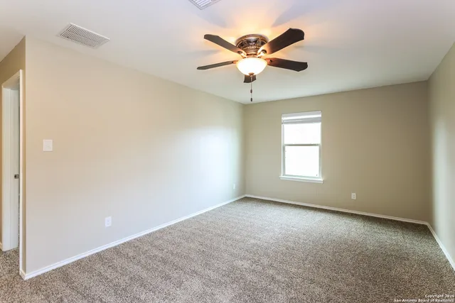 an empty room with windows and fan