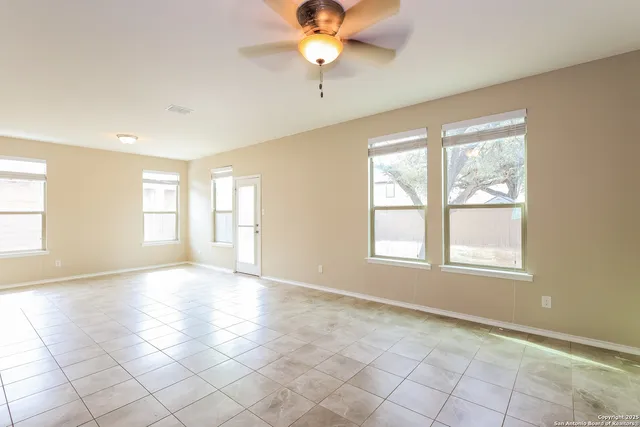 a view of an empty room with window and chandelier fan