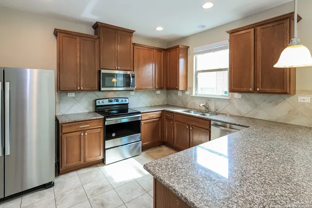 a kitchen with granite countertop wooden cabinets and a stove top oven