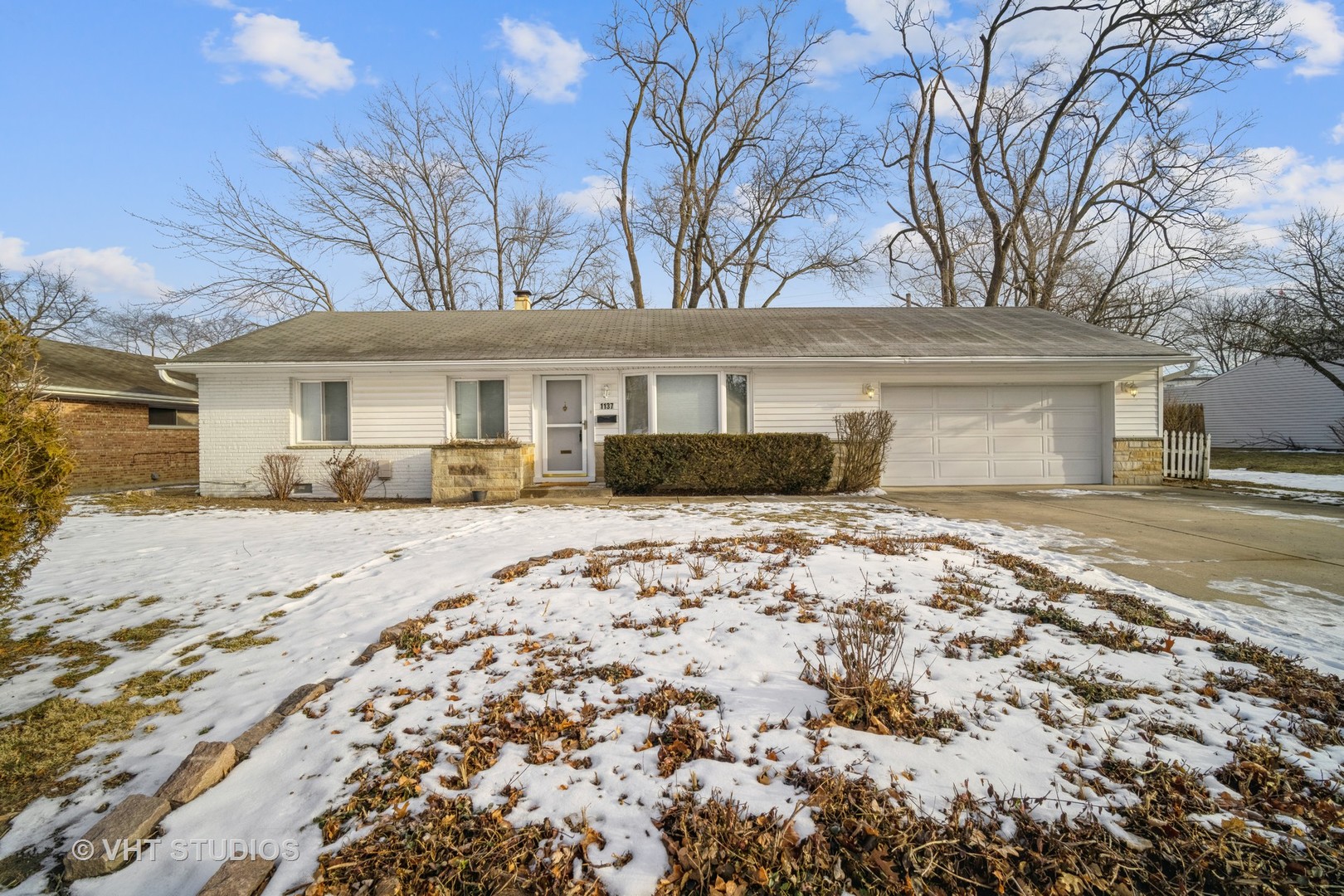 a front view of a house with a yard covered in snow