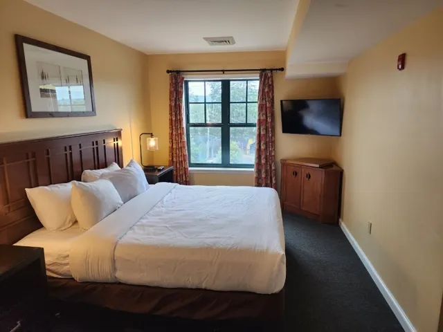 a bedroom with a bed and a flat tv screen next to a large window