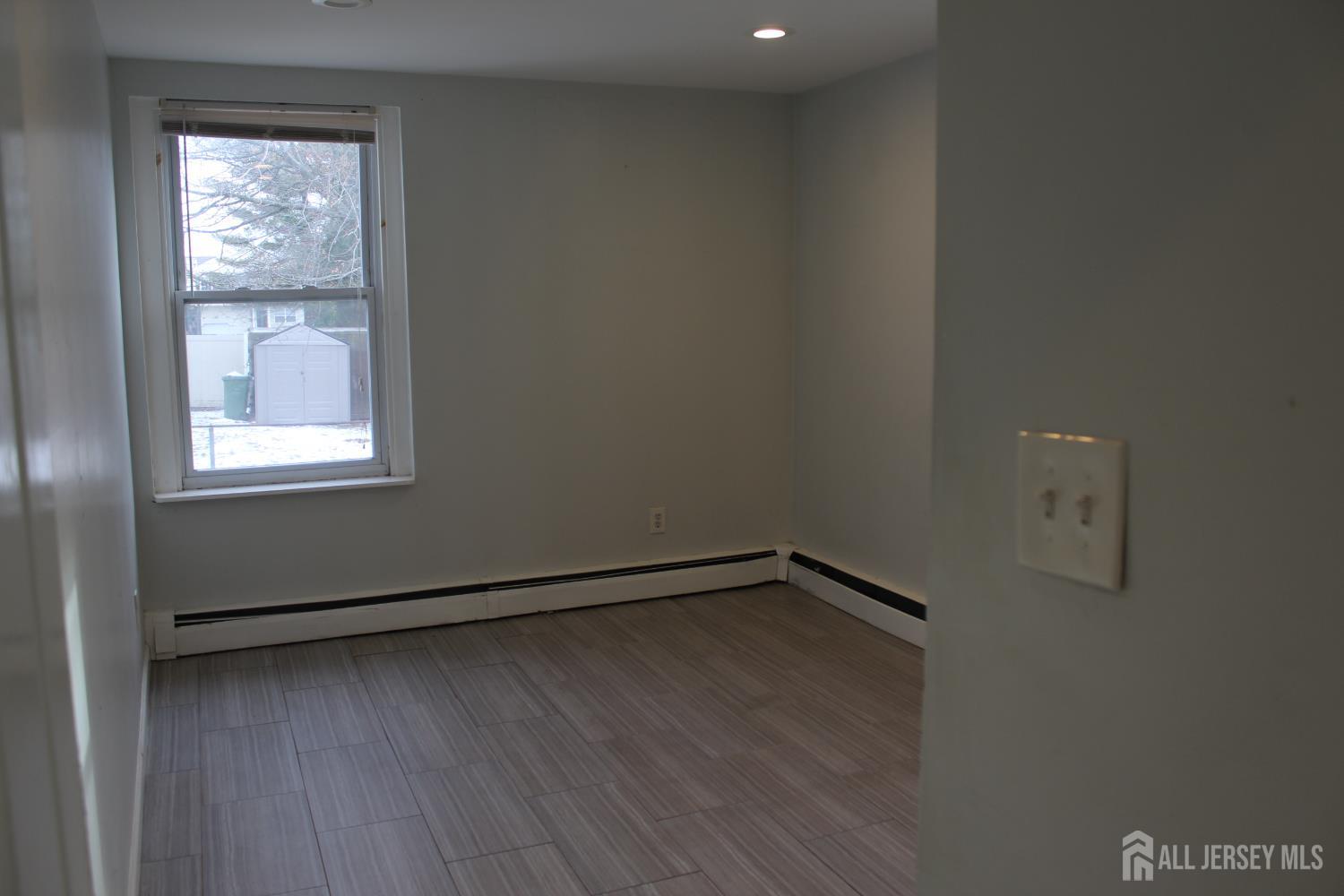 899 Green Street, Unit 1 Iselin, NJ 08830 - Photo 26 of 45 an empty room with wooden floor and windows
