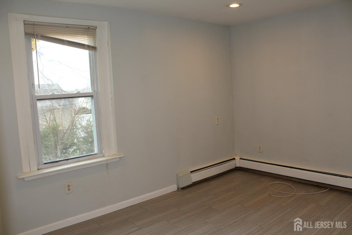 899 Green Street, Unit 1 Iselin, NJ 08830 - Photo 34 of 45 an empty room with wooden floor and windows