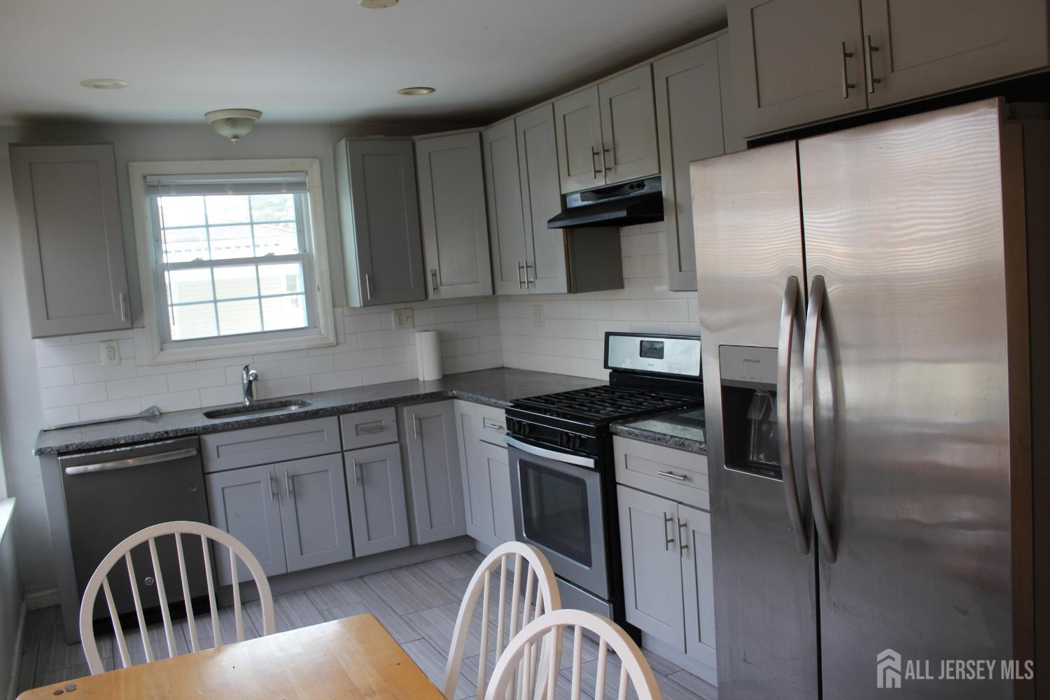 899 Green Street, Unit 1 Iselin, NJ 08830 - Photo 4 of 45 a kitchen with stainless steel appliances granite countertop a refrigerator a sink a stove a table and chairs
