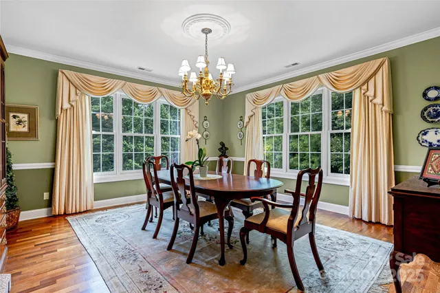 a view of a dining room with furniture a chandelier and large windows