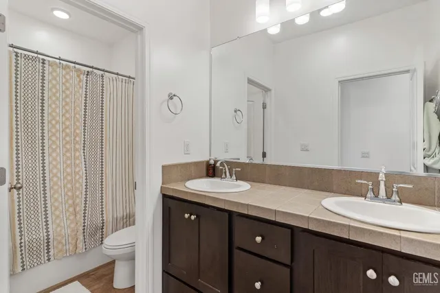 a bathroom with a granite countertop sink a toilet a mirror and shower