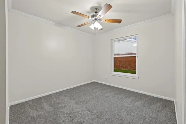 an empty room with windows and chandelier fan