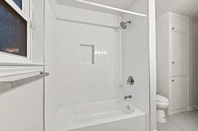 a bathroom with a bathtub shower and toilet
