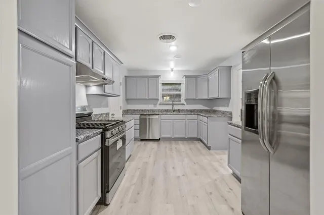 a kitchen with stainless steel appliances a refrigerator sink and cabinets