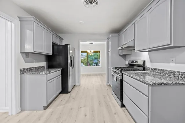 a kitchen with stainless steel appliances granite countertop a stove a refrigerator and a sink