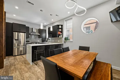 a kitchen with stainless steel appliances granite countertop a sink dishwasher a stove a refrigerator with a dining table and chairs