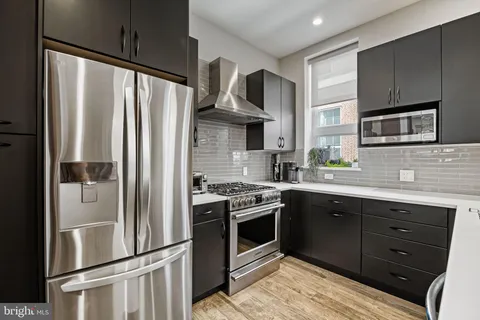 a kitchen with stainless steel appliances granite countertop a refrigerator a stove and a sink