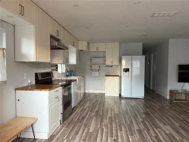 a kitchen with a refrigerator a stove top oven a sink dishwasher and white cabinets with wooden floor