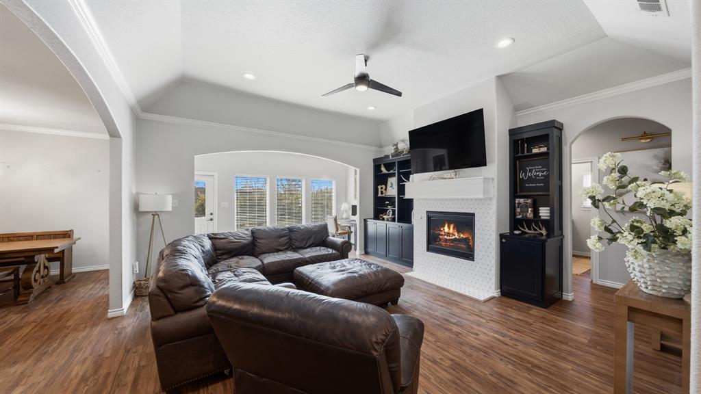 101 Lighthouse Lane Mabank, TX 75143 - Photo 4 of 40 Living room with arched walkways, ceiling fan, crown molding, built in shelves, and dark wood-style flooring