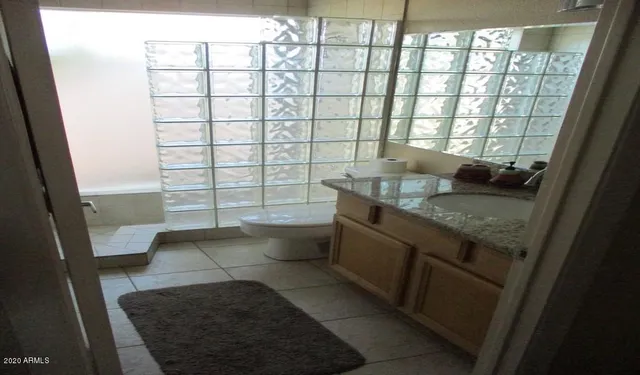 a bathroom with a granite countertop sink a toilet and a mirror