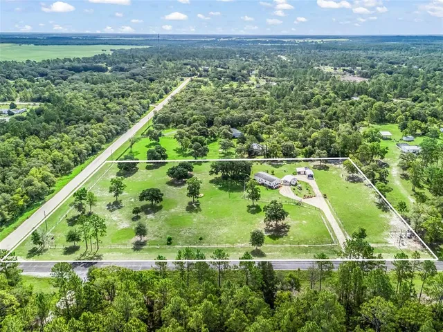 an aerial view of a house with outdoor space patio and trees all around