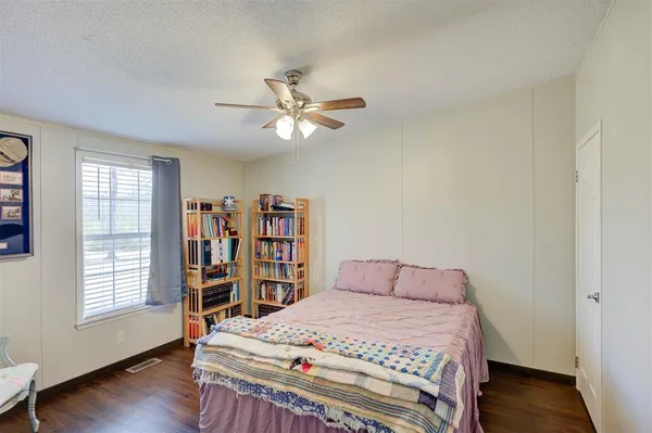a bedroom with a bed a dresser and wooden floor