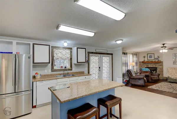 a kitchen with stainless steel appliances granite countertop a refrigerator a sink dishwasher a stove and a refrigerator with wooden floor