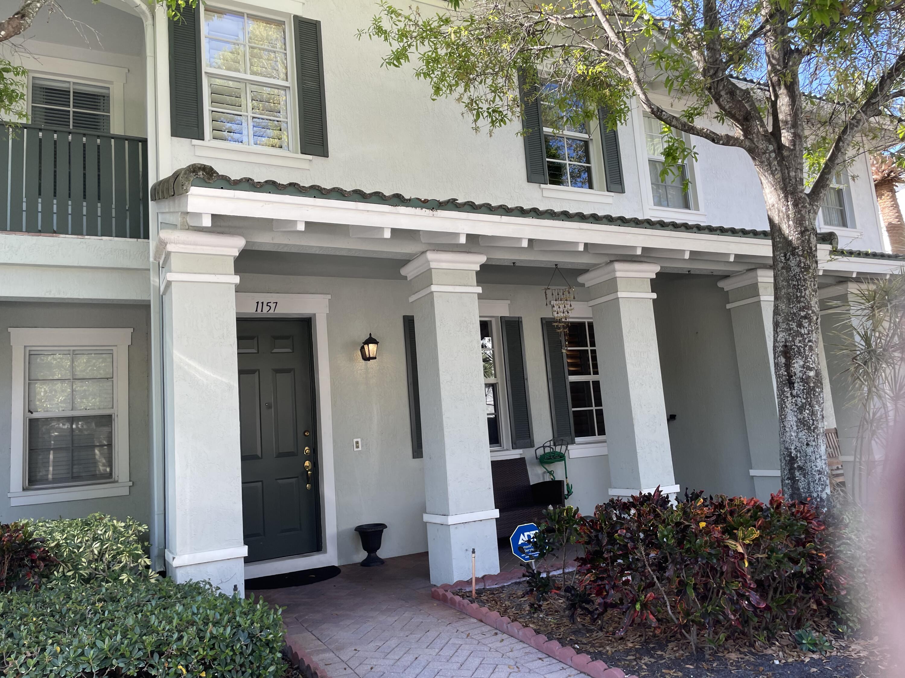 a view of a house with a potted plant and a large tree