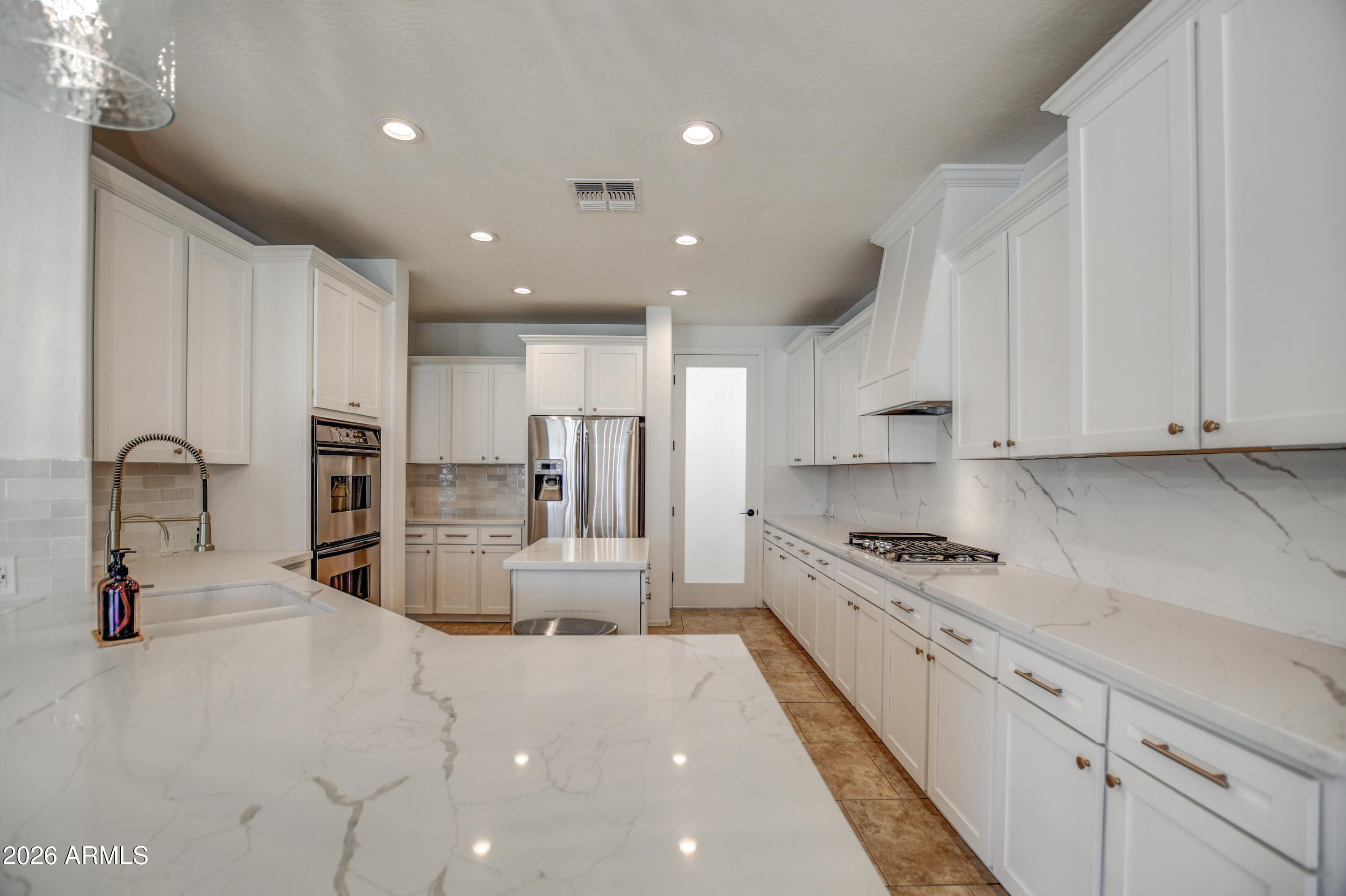 3078 East Muirfield Street Gilbert, AZ 85298 - Photo 34 of 92 a large kitchen with stainless steel appliances granite countertop a stove a sink a refrigerator and white cabinets with wooden floor