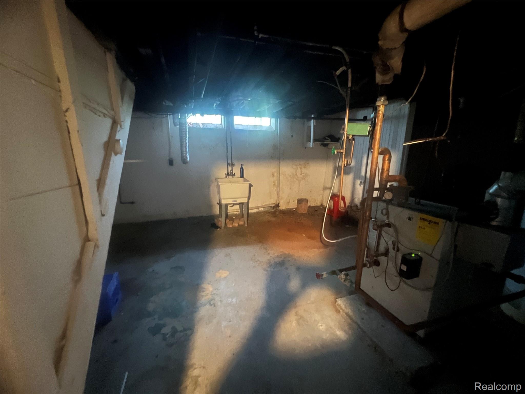 17311 Santa Rosa Drive Detroit, MI 48221 - Photo 50 of 89 Basement utility area featuring a wall-mounted laundry sink, exposed overhead ductwork, and an installed water heater system