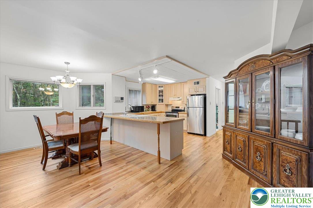 131 Stone Ridge Albrightsville, PA 18210 - Photo 13 of 51 a open kitchen with stainless steel appliances kitchen island granite countertop a refrigerator a stove a dining table and chairs with wooden floor
