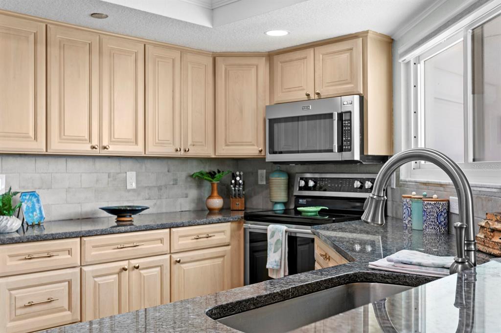 16332 Gulf Boulevard, Unit 3B Redington Beach, FL 33708 - Photo 23 of 91 a kitchen with stainless steel appliances granite countertop a stove a sink and white cabinets