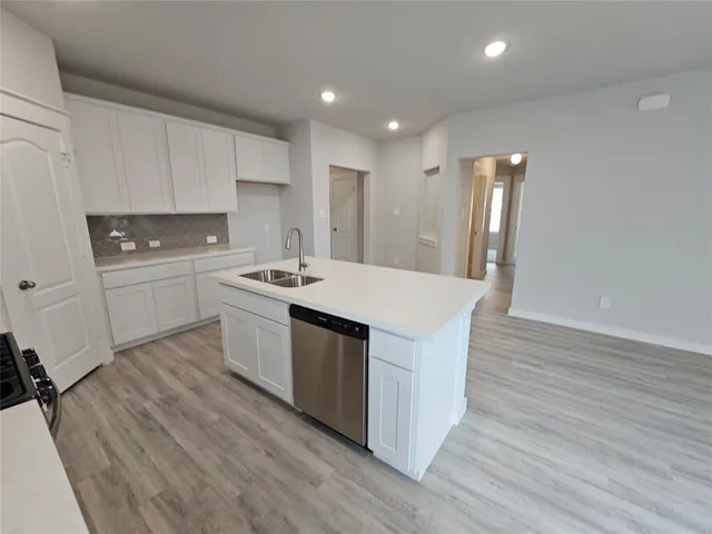 a kitchen with a sink a stove a refrigerator and white cabinets