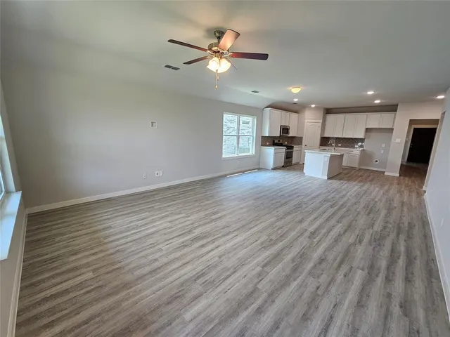 a view of a livingroom with furniture a ceiling fan and wooden floor