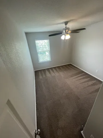 an empty room with windows and fan