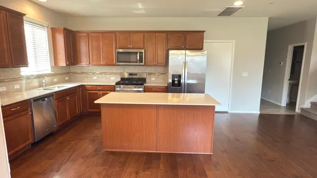 a kitchen with stainless steel appliances granite countertop a sink a stove a refrigerator cabinets and wooden floor