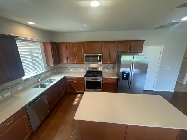 a large kitchen with a large counter top stainless steel appliances and a window