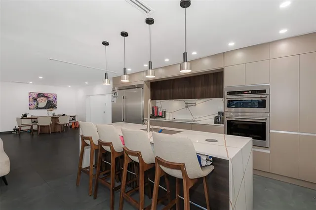 a kitchen with stainless steel appliances kitchen island granite countertop a stove a refrigerator a kitchen island a dining table and chairs with wooden floor