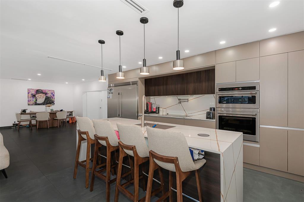 a kitchen with stainless steel appliances kitchen island granite countertop a stove a refrigerator a kitchen island a dining table and chairs with wooden floor