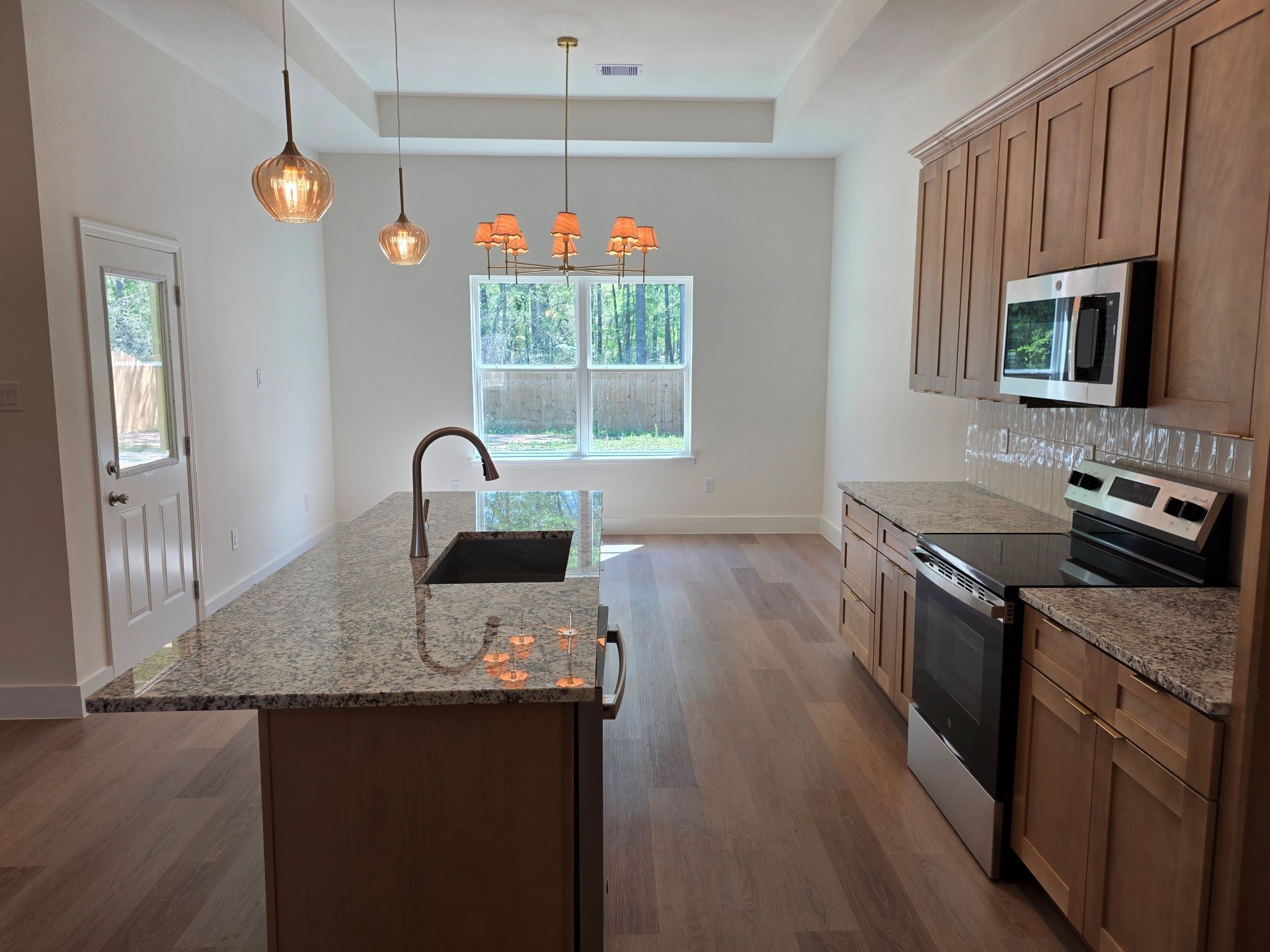 16280 Jeet Street Conroe, TX 77306 - Photo 9 of 31 a kitchen with stainless steel appliances granite countertop a sink a stove and a wooden floors