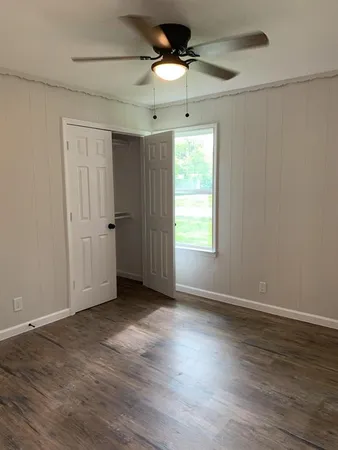 an empty room with wooden floor and fan