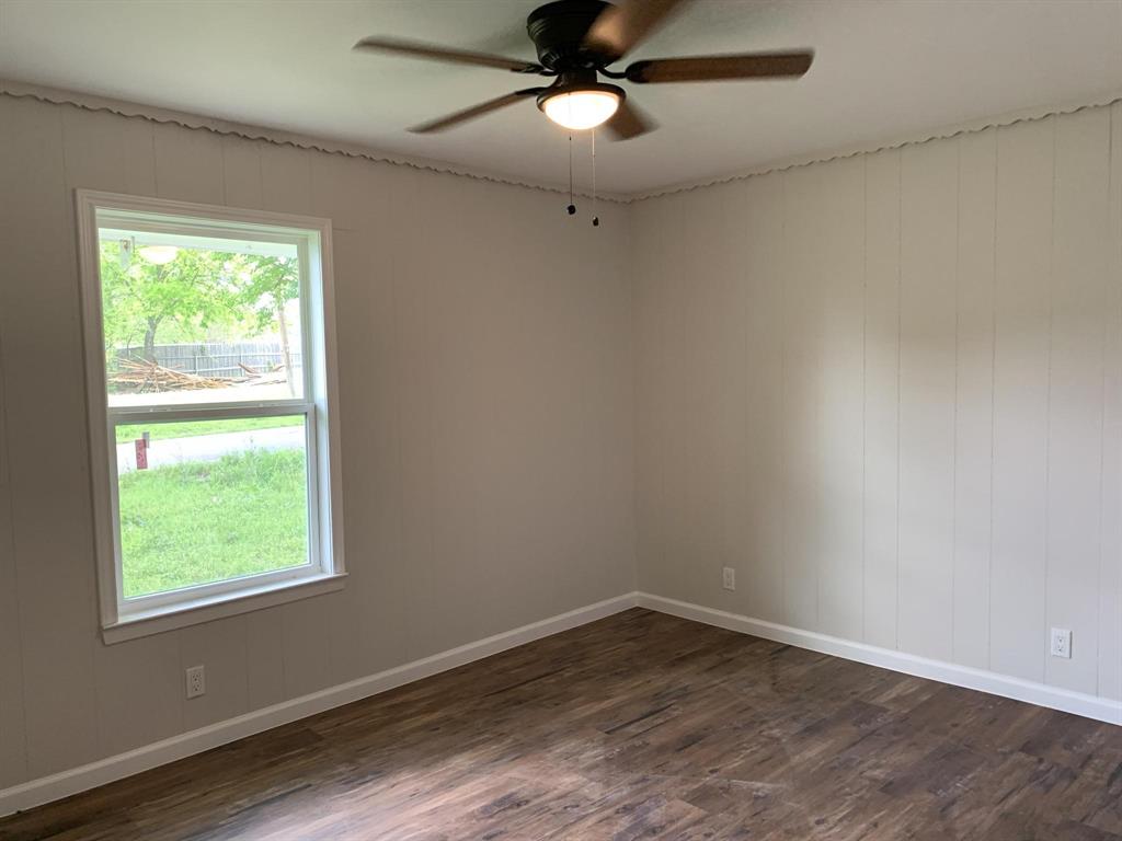 105 Still Street Kemp, TX 75143 - Photo 16 of 28 Spare room featuring a ceiling fan, dark wood-style floors, and wooden walls
