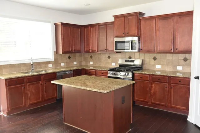 a kitchen with stainless steel appliances granite countertop a sink stove and microwave