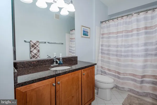 a bathroom with a granite countertop sink a toilet and a mirror