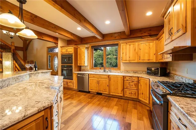 a view of kitchen with stainless steel appliances refrigerator stove and wooden floor