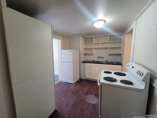 a kitchen with a refrigerator a stove top oven and cabinets