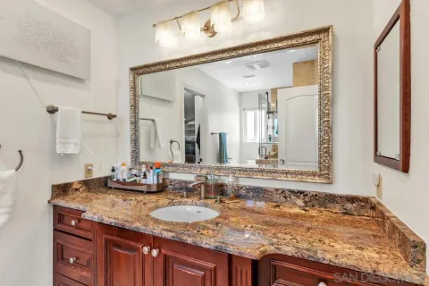 a bathroom with a granite countertop bathtub shower sink mirror and toilet