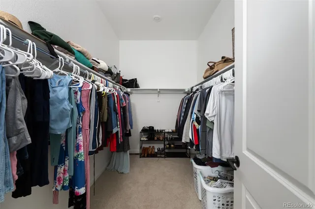 a view of walk in closet with clothes and shoes