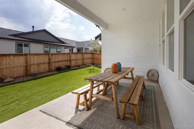 a view of a patio with table and chairs with wooden floor and fence